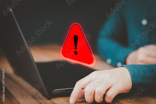 Fototapeta Naklejka Na Ścianę i Meble -  Adult man using a computer laptop with triangle caution warning sign for notification error. Concept technology of computer virus detected, personal data protection, network security and maintenance.