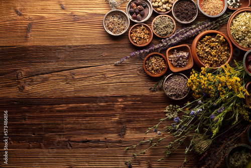 Natural medicine background. Assorted dry herbs in bowls, mortar and plants on rustic wooden table.