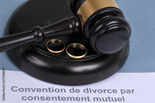 Concept de divorce par consentement mutuel avec des alliances et un marteau de juge sur fond bleu