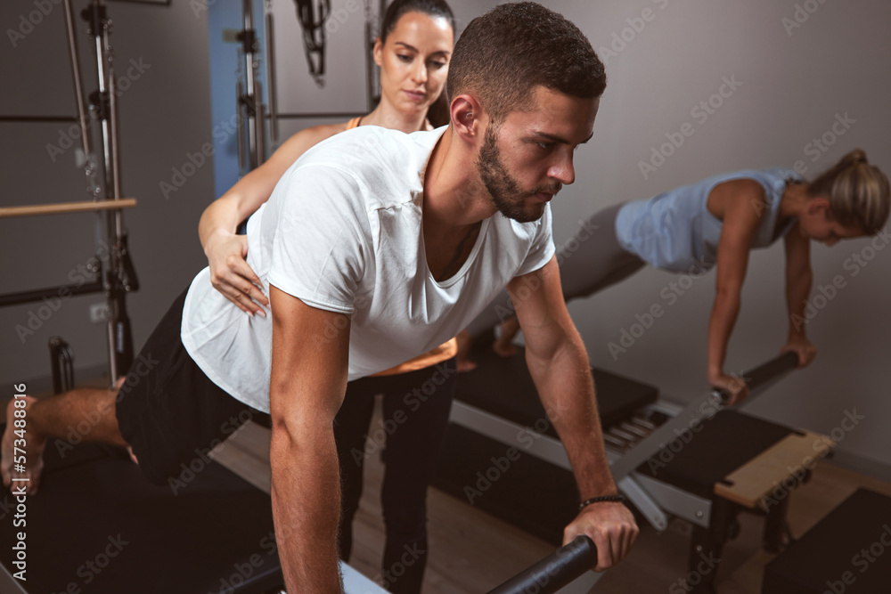 Young women and man exercising in a gym with personal trainer. Young women and man exercising in a gym with personal trainer.