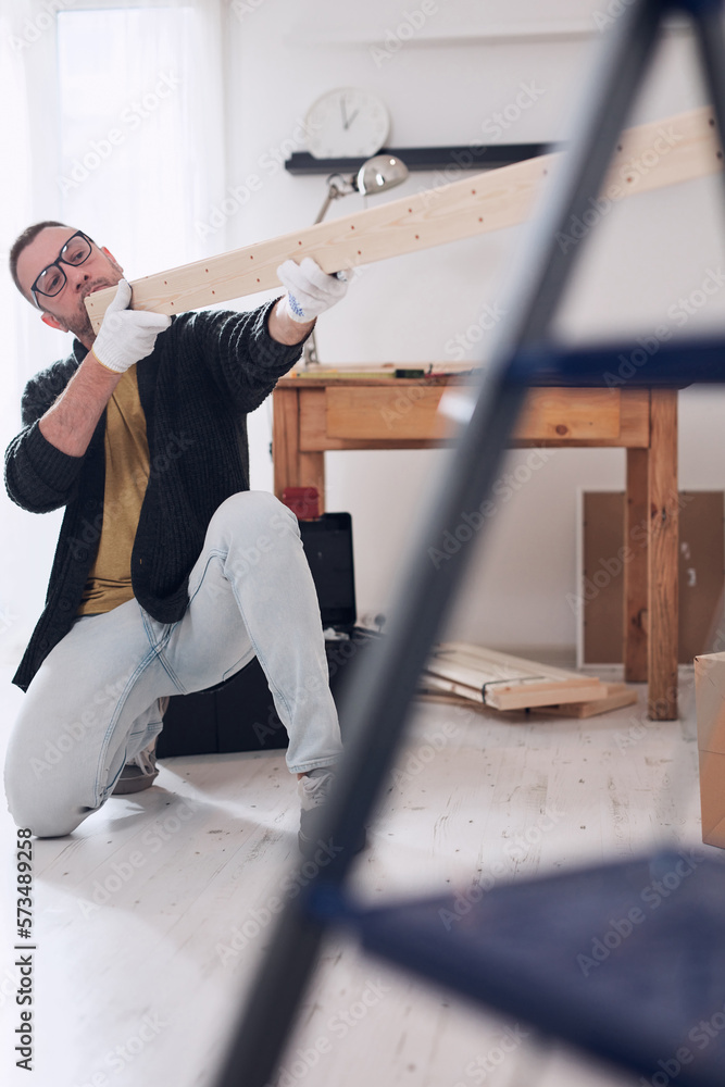 Man assembling new wooden shelf and furniture in the apartment. Man assembling new wooden shelf and furniture in the apartment.
