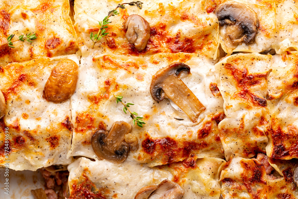Close-up of homemade white lasagna with porcini and champignon mushrooms, onion and sausages. Pasta with parmesan cheese and bechamel sauce.
