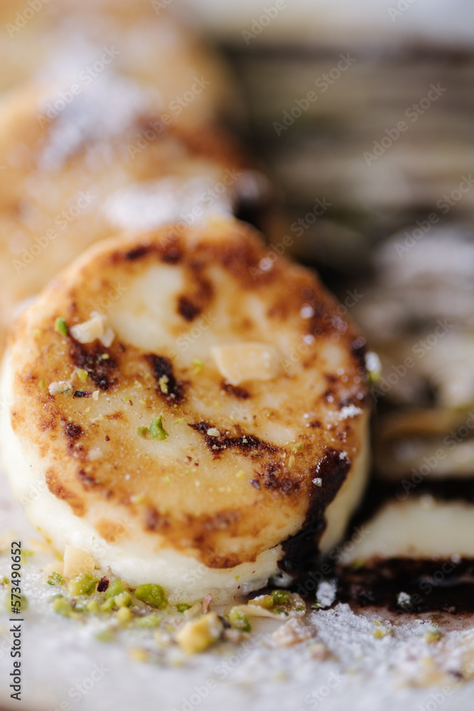 Macro photo cheesecakes fried in butter with creamy chocolate cream, grated nuts on top Macro photo cheesecakes fried in butter with creamy chocolate cream, grated nuts on top