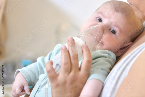 A sick child breathes with a nebulizer mask with a steam inhaler due to a respiratory disease. A mother holding an inhaler in her hands.