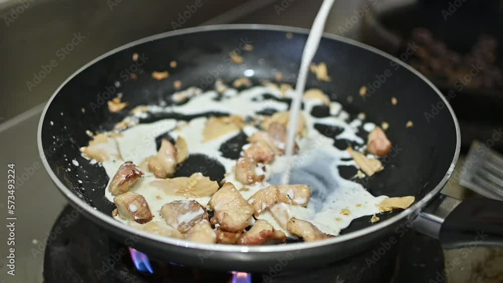 White Cream Sauce Being Poured Over Cut Meat Pieces In Frying Pan. Slow Motion White Cream Sauce Being Poured Over Cut Meat Pieces In Frying Pan. Slow Motion