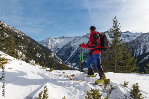 Ski mountaineer in winter, Italian Alps, Macugnaga. Man skier with ski touring equipment. Concept of sport, freedom and adventure. The village of Borca is visible below 