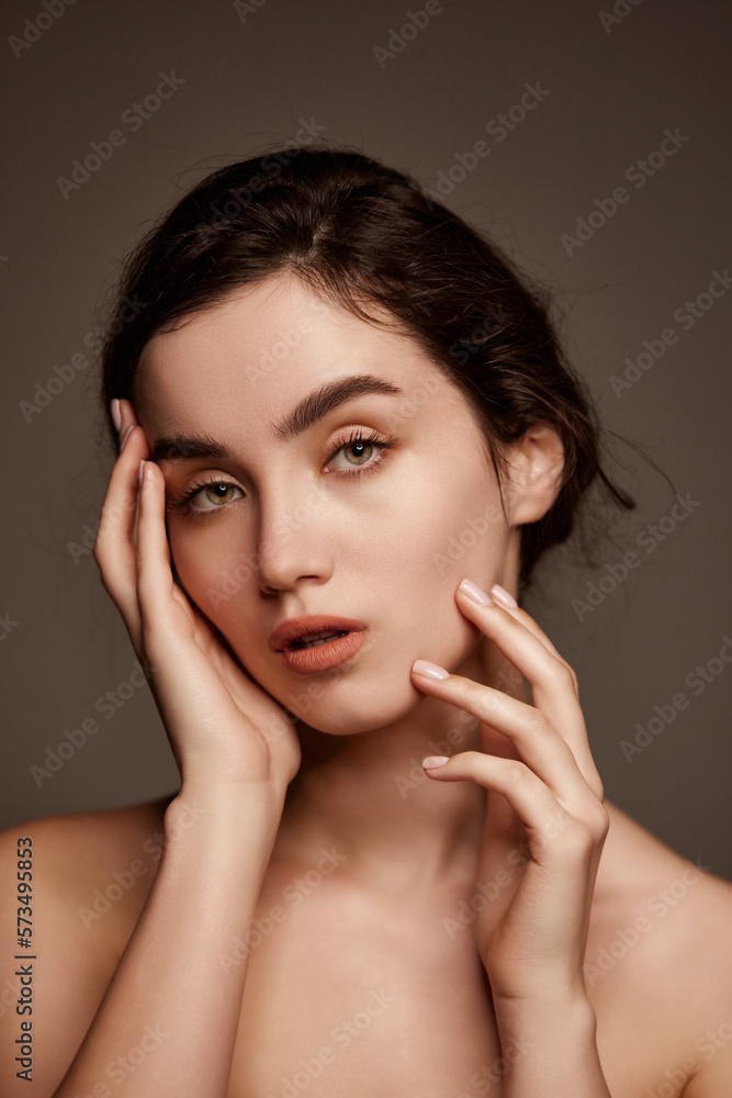Tenderness. Portrait of young beautiful girl with brown hair and nude makeup style posing over dark grey studio background. Concept of natural beauty, skincare, cosmetology, plastic surgery, health Tenderness. Portrait of young beautiful girl with brown hair and nude makeup style posing over dark grey studio background. Concept of natural beauty, skincare, cosmetology, plastic surgery, health