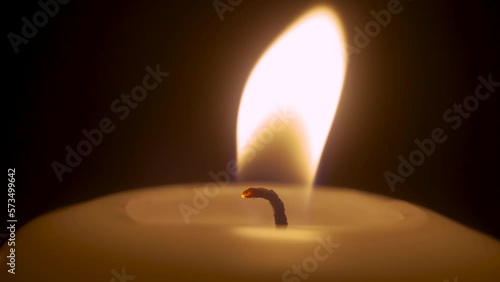 Single white candle burning and extinguish by wind blowing. Isolated candlelight with dark background. Paraffin candle with yellow shades burns. Lifestyle remembrance celebration religious