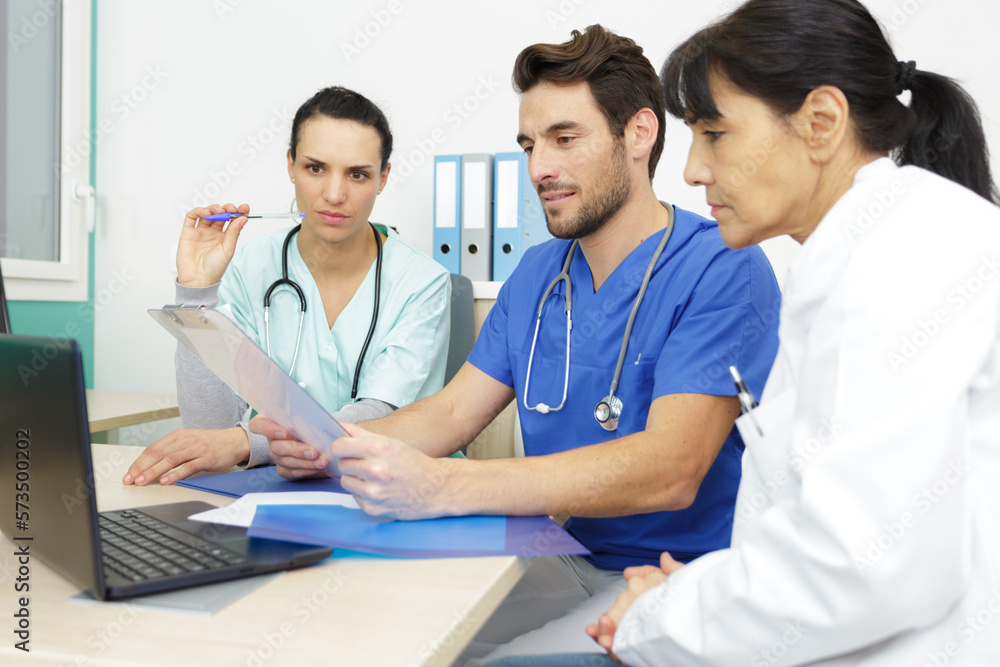 team of doctors working on laptop in medical office team of doctors working on laptop in medical office