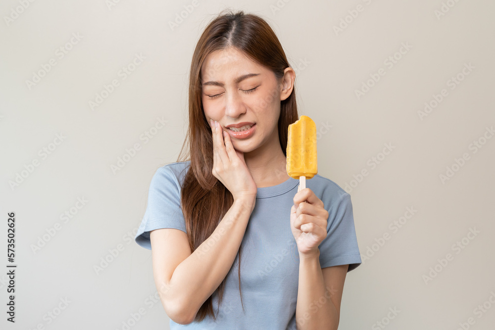 Face expression suffering from sensitive teeth, Asian young woman touching cheek Face expression suffering from sensitive teeth, Asian young woman touching cheek