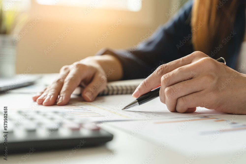 Women business people use calculators to calculate the company budget and income reports on the desk in the office. - obrazy, fototapety, plakaty 