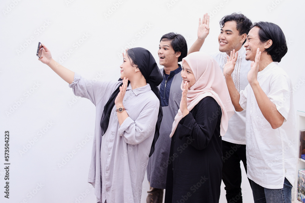 Young muslim people taking selfie or having video call during eid mubarak moment, isolated over white background. Young muslim people taking selfie or having video call during eid mubarak moment, isolated over white background.