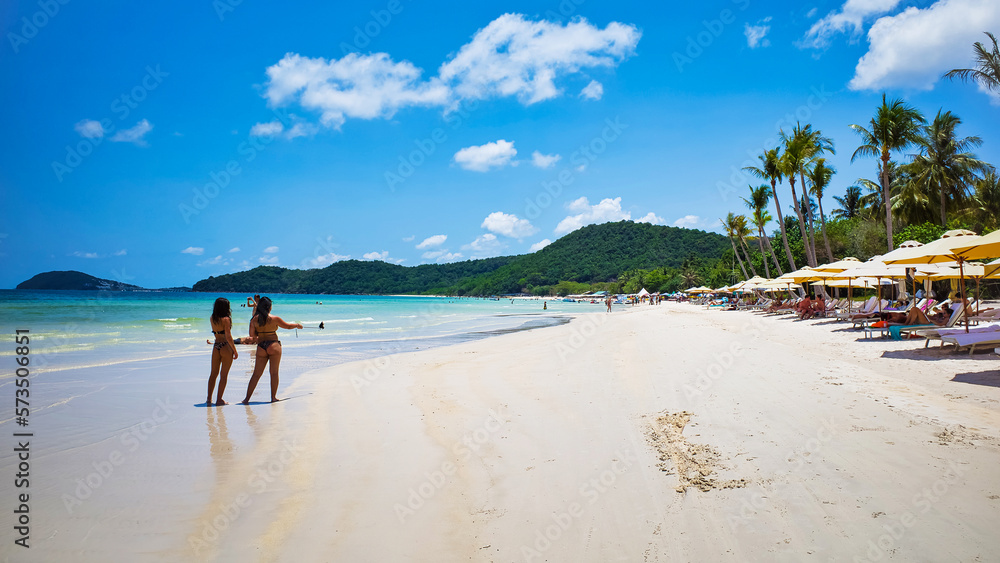 Phu Quoc island, Vietnam - March 31, 2019: White sand beach, calm sea. Rocky hills, clear skies, tall palm trees and tropical trees. Beautiful coast of the South China Sea