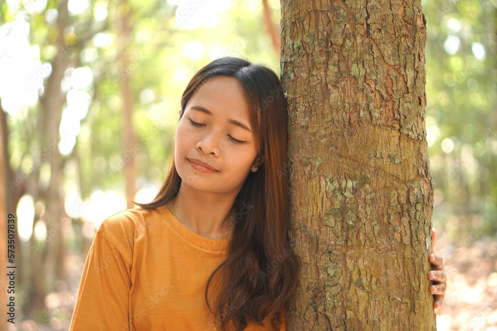 concept of saving the world Asian woman holding a tree with her eyes closed to experience the power of nature concept of saving the world Asian woman holding a tree with her eyes closed to experience the power of nature