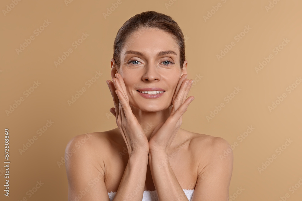 Woman massaging her face on beige background Woman massaging her face on beige background