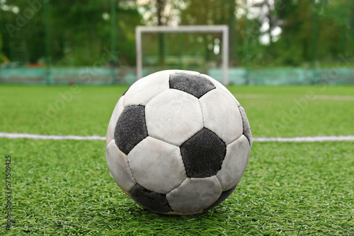 Dirty soccer ball on green football field, closeup © New Africa