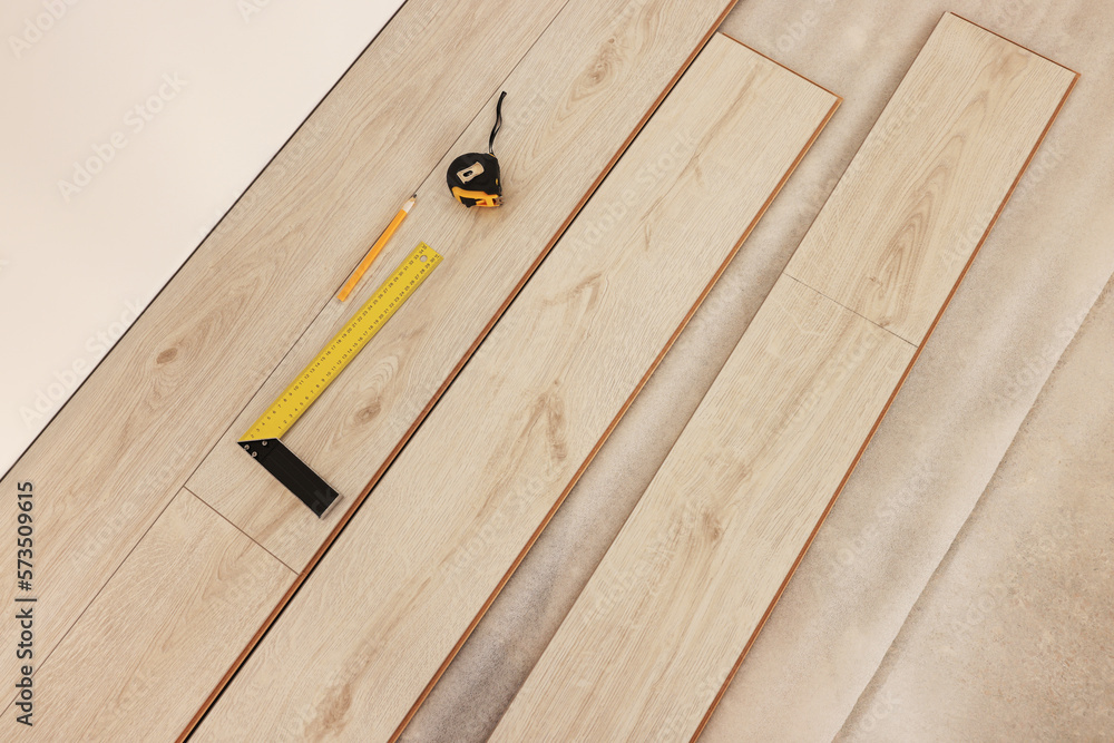 Parquet planks, ruler, pencil and measuring tape on floor in room prepared for renovation, top view Parquet planks, ruler, pencil and measuring tape on floor in room prepared for renovation, top view