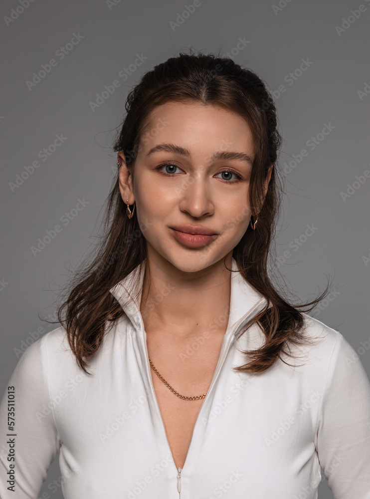 Portrait of a beautiful young girl on a gray background in the studio with light makeup and accessories Portrait of a beautiful young girl on a gray background in the studio with light makeup and accessories