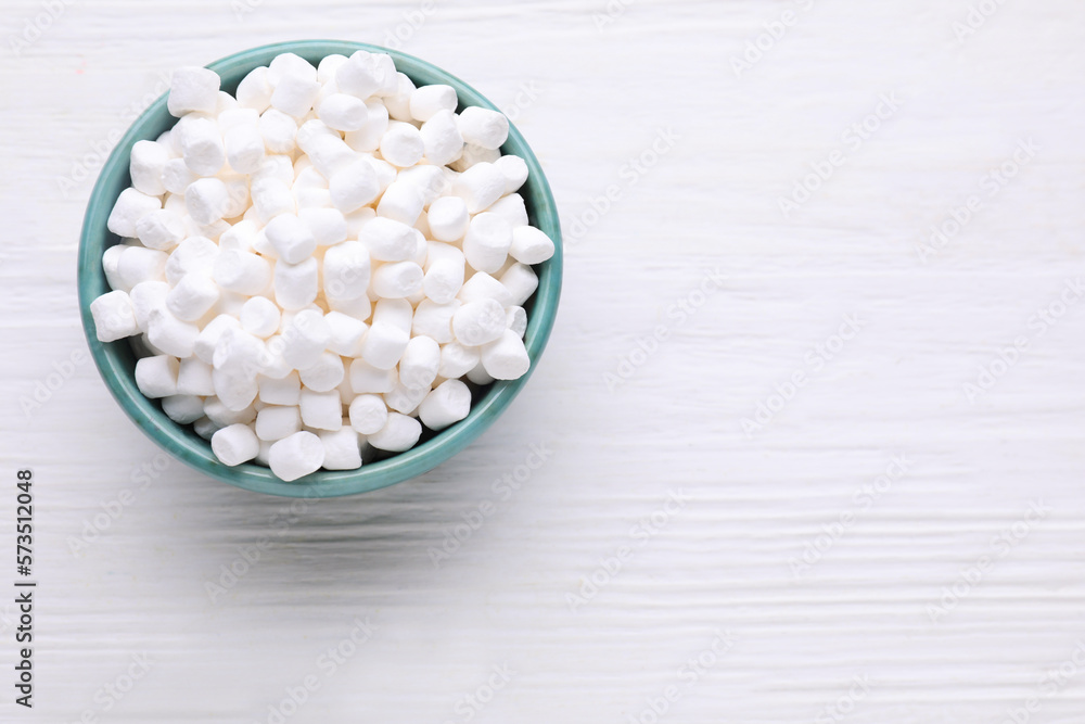 Bowl with delicious marshmallows on white wooden table, top view. Space for text Bowl with delicious marshmallows on white wooden table, top view. Space for text