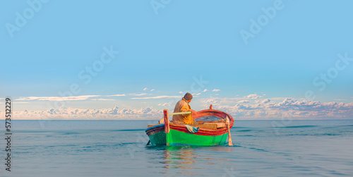 Fisherman with fishing boat in a calm sea in the background 