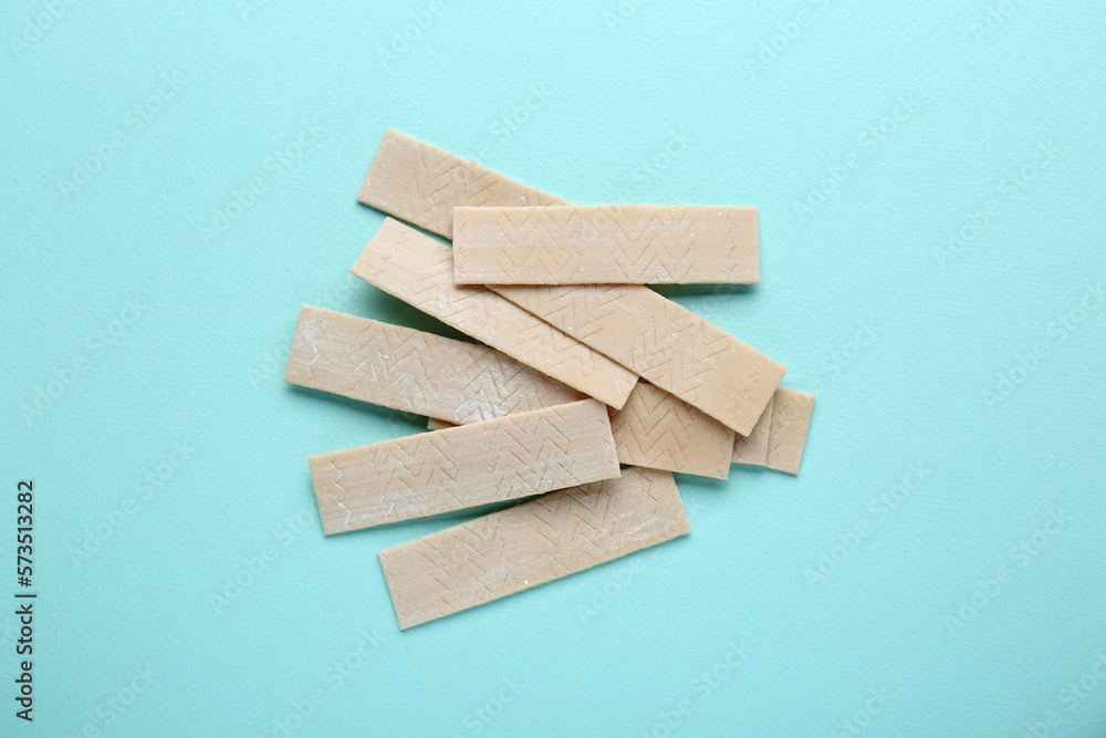 Many sticks of tasty chewing gum on light blue background, flat lay