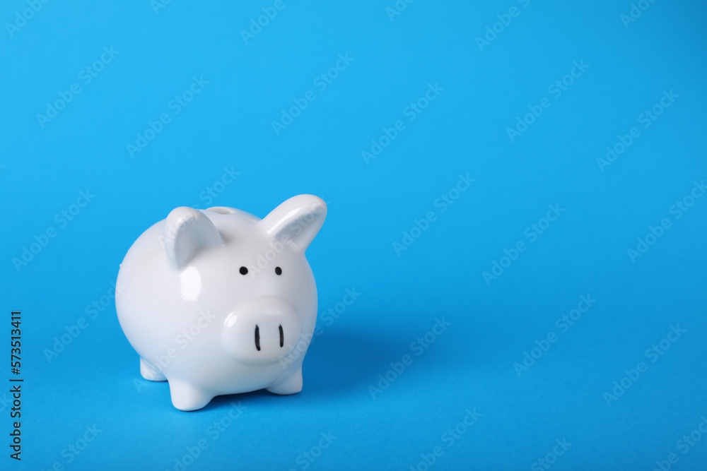 Ceramic piggy bank on light blue background, space for text. Financial savings
