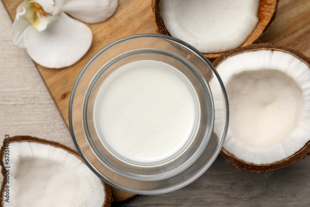 Glass of delicious vegan milk, coconuts and flower on white wooden table, flat lay Glass of delicious vegan milk, coconuts and flower on white wooden table, flat lay