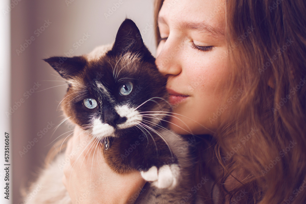 Close up of lovely young woman kissing cat at home