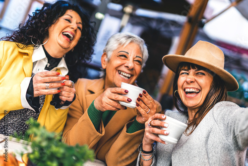 Group of mature women having  fun at the café bar enjoying breakfast drinking coffee- Three senior female  taking selfie with smart phone outdoors at cafeteria dehor-Life style concept 