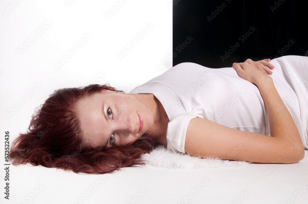 Portrait of a red-haired woman in a white dress lying in the studio Portrait of a red-haired woman in a white dress lying in the studio