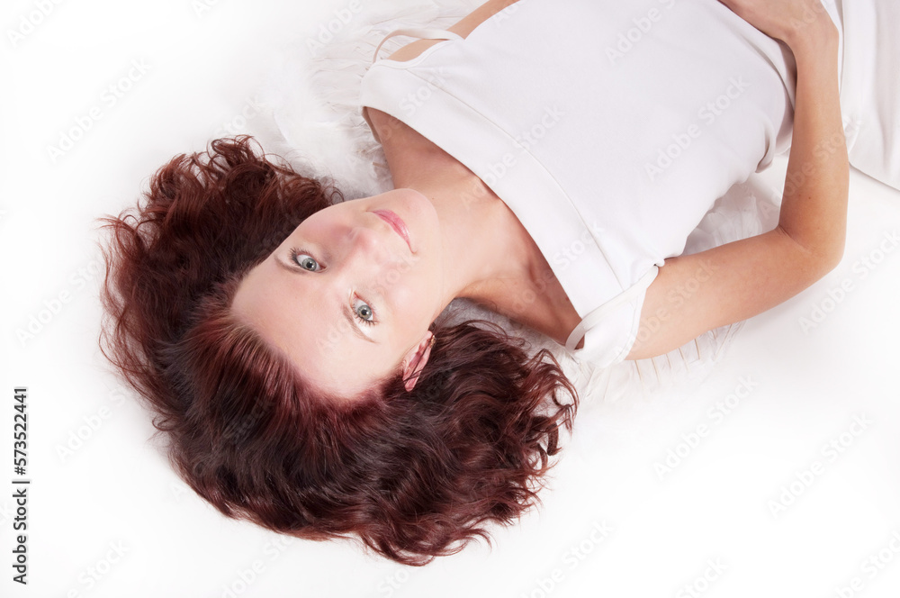 Portrait of a red-haired woman in a white dress lying in the studio Portrait of a red-haired woman in a white dress lying in the studio