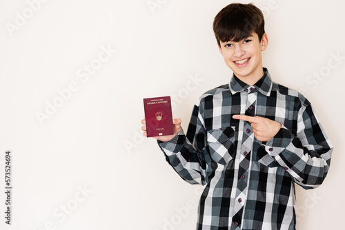 Fotografija Young teenager boy holding Slovenia passport looking positive and happy standing and smiling with a confident smile against white background