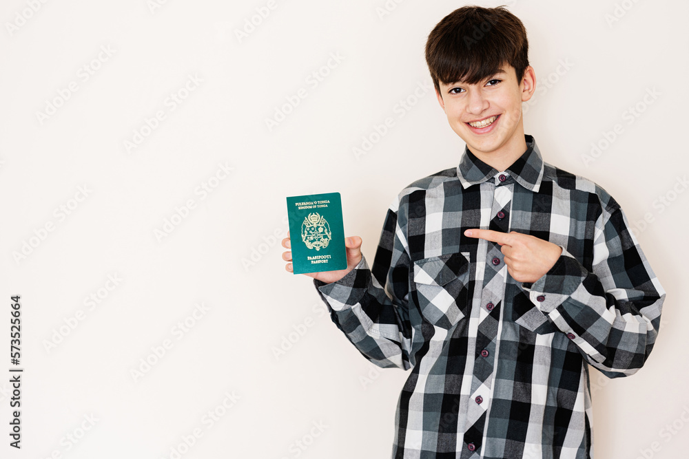 Young teenager boy holding Tonga passport looking positive and happy standing and smiling with a confident smile against white background. Young teenager boy holding Tonga passport looking positive and happy standing and smiling with a confident smile against white background.