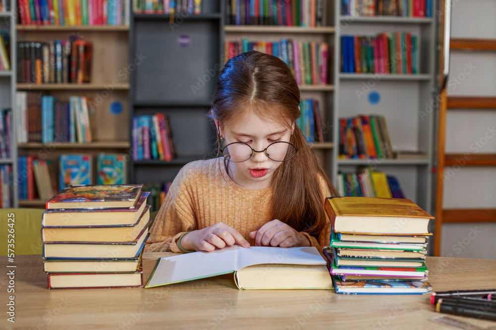 Little student girl with many books at school or library. Education and school concept. Little student girl with many books at school or library. Education and school concept.