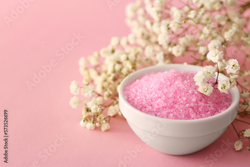 Aromatic sea salt and beautiful flowers on pink background, closeup. Space for text