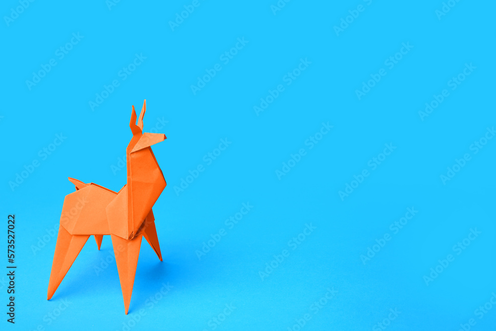 Origami art. Handmade orange paper deer on light blue background, space for text Origami art. Handmade orange paper deer on light blue background, space for text