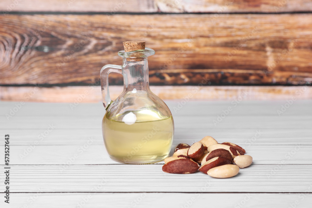 Obraz premium Tasty Brazil nuts and bottle with oil on white wooden table