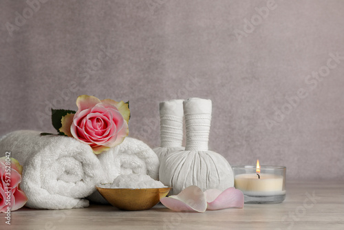 Composition with spa products, roses and candle on grey wooden table. Space for text