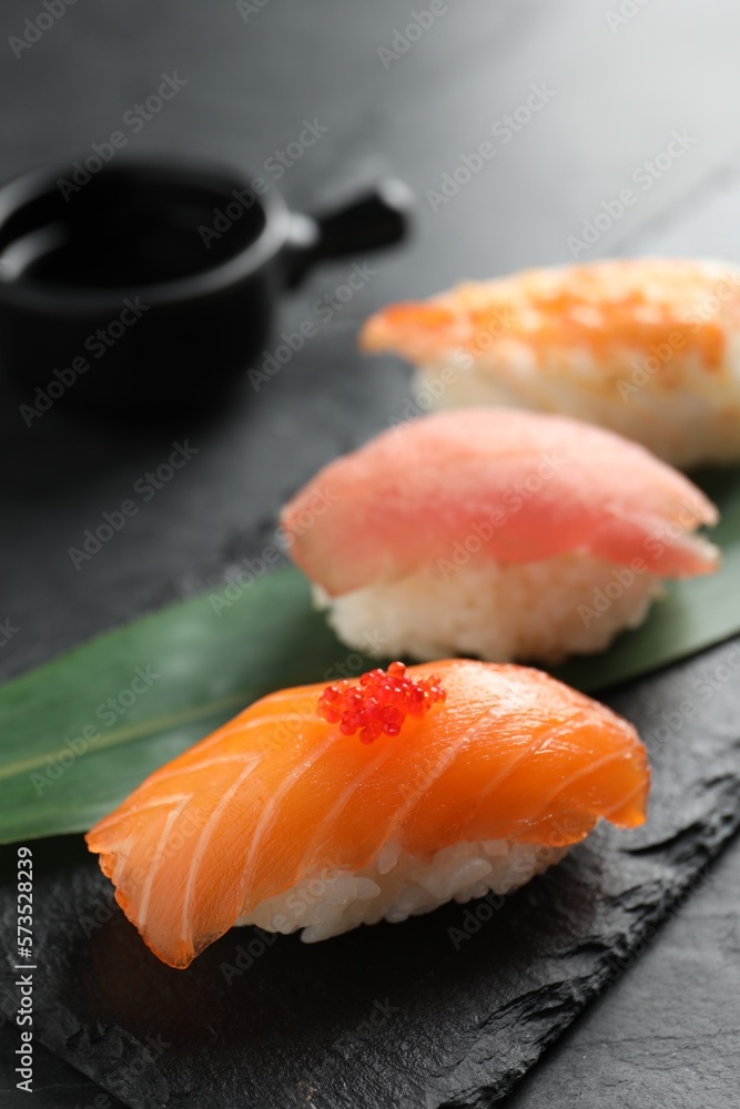 Serving board with delicious nigiri sushi and soy sauce on black table, closeup Serving board with delicious nigiri sushi and soy sauce on black table, closeup