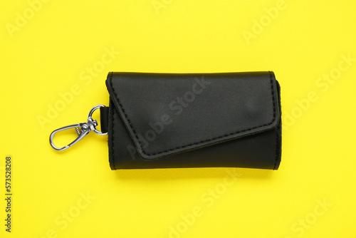 Stylish leather keys holder on yellow background, top view
