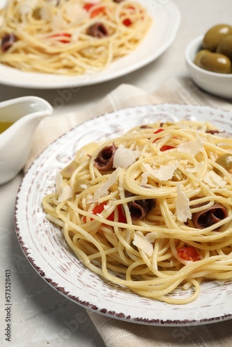 Delicious pasta with anchovies, tomatoes and parmesan cheese on light grey table