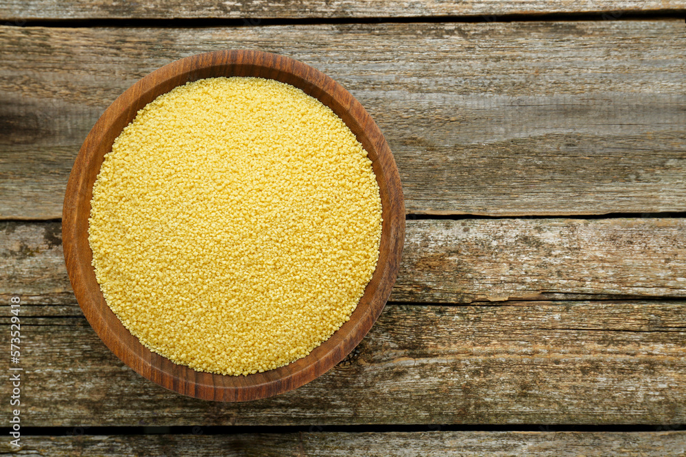 Bowl of raw couscous on wooden table, top view. Space for text Bowl of raw couscous on wooden table, top view. Space for text