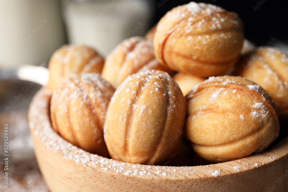 Delicious nut shaped cookies with powdered sugar in wooden bowl, closeup