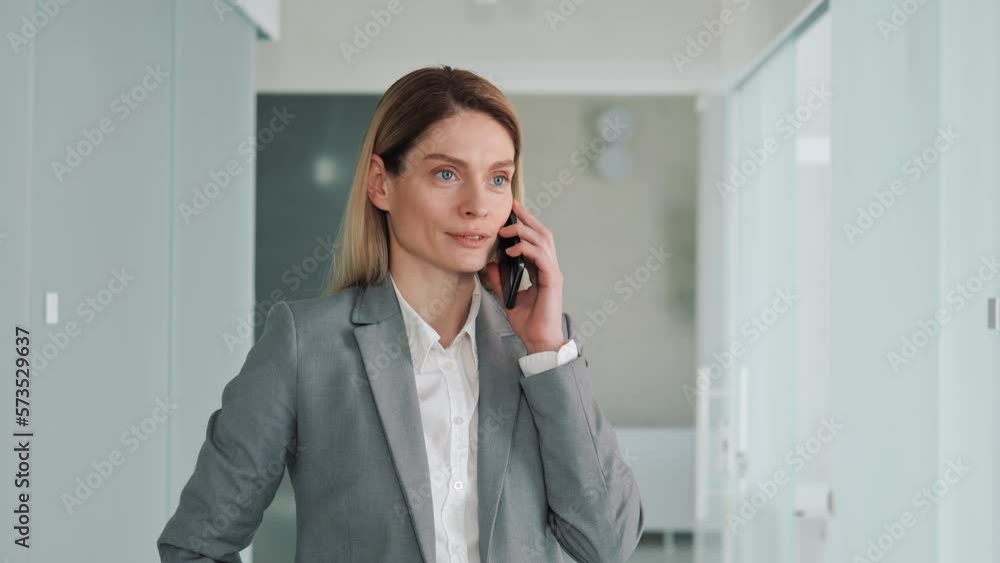 Cheerful beautiful blue eyes businesswoman making mobile call in office hall. Office manager talking on smartphone consulting bank client remotely. Successful adviser discussing project with partner. Cheerful beautiful blue eyes businesswoman making mobile call in office hall. Office manager talking on smartphone consulting bank client remotely. Successful adviser discussing project with partner.