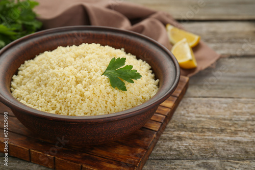 Tasty couscous with parsley on wooden table, closeup