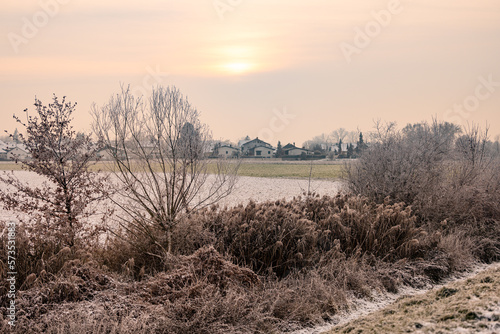 Snowy landscape in front of a settlement in winter with atmospheric sunset © reisezielinfo