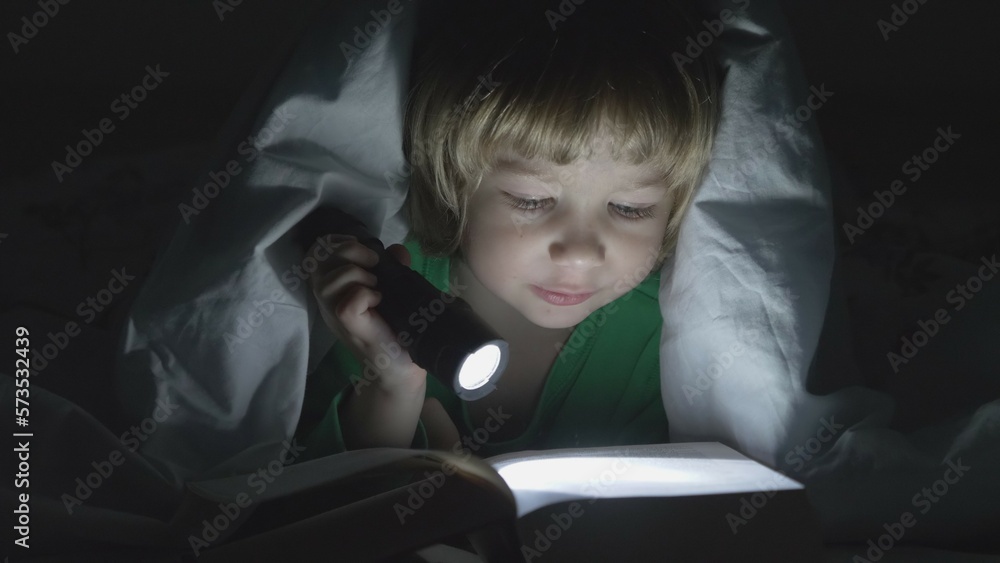 Funny little blond hair child with lamp reading loud a book, boy covered Funny little blond hair child with lamp reading loud a book, boy covered