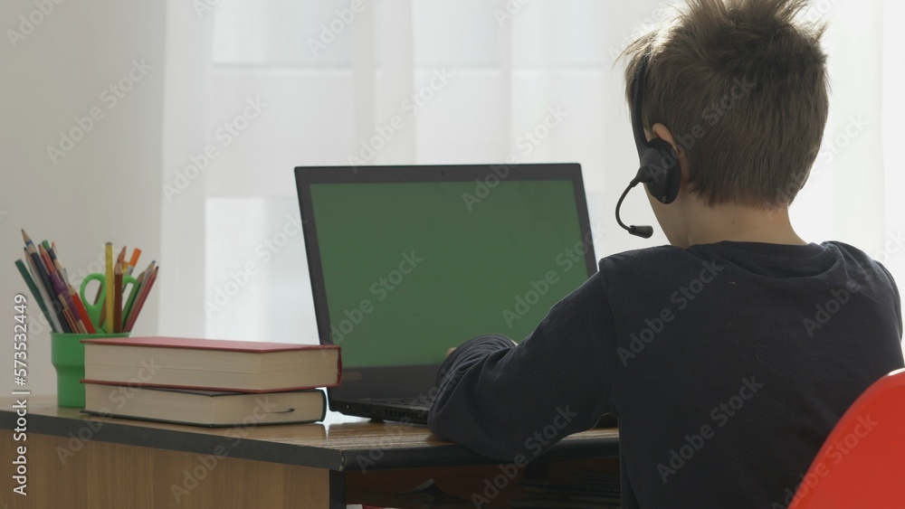 Child with back sit at desk, green computer screen, school online Child with back sit at desk, green computer screen, school online