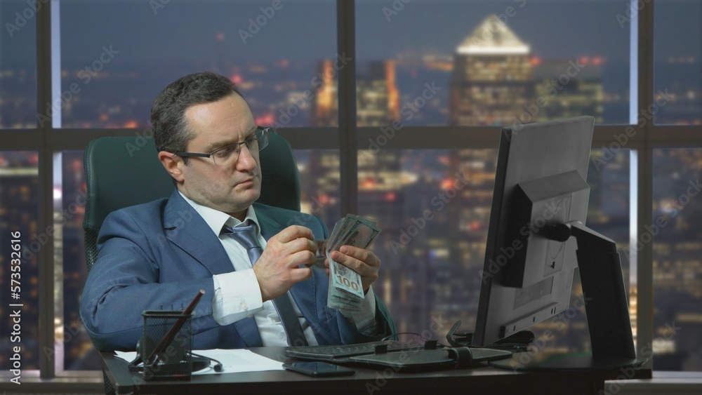 Businessman counting banknotes at the office at night Businessman counting banknotes at the office at night