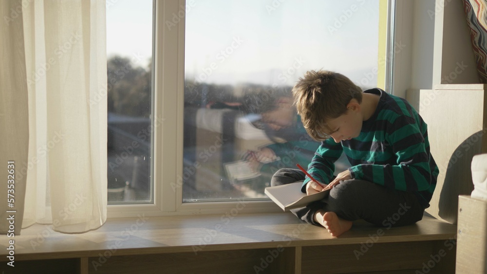 Child sit at window and drawing on notebook, smart hobby in modern life